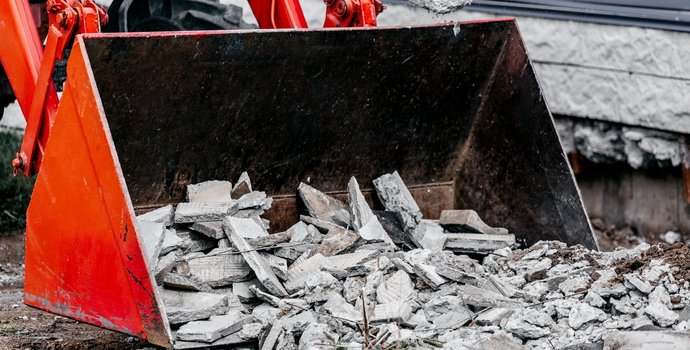 cement debris being hauled by an excavator