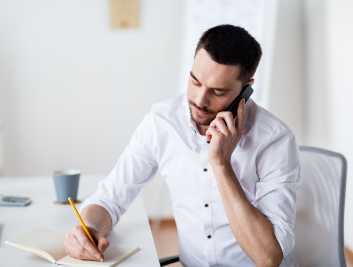 contractor calling a dumpster company while writing notes